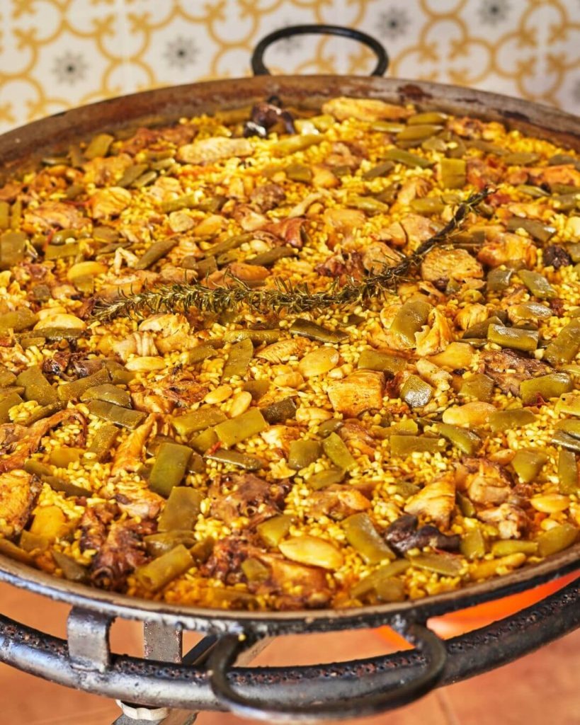 Paella valenciana tradicional cocinada con ingredientes frescos de Km 0.